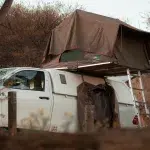 Weißes Auto mit aufgestelltem Dachzelt auf einem Campingplatz am Lake Oanob in Namibia.