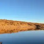 Blick auf See mit Felsformation, die sich im Wasser spiegelt