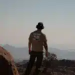 Mann von hinten steht auf Felsvorsprung und schaut in die Ferne