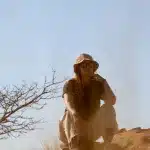 Frau sitzt auf Felsvorsprung in Namibgrens und schaut in die Ferne