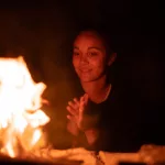 Frau sitzt nachts am Lagerfeuer