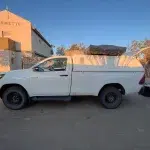 Weißes Auto steht auf einem Campingplatz vor einer Waschhäuschen