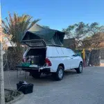 Auto mit Dachtzelt und geöffneter Heckklappe auf einem Campingplatz