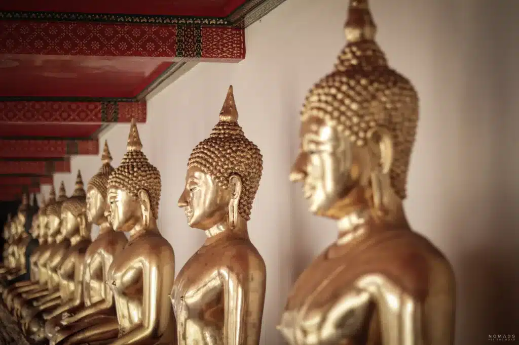 Goldene Buddhastatuen nebeneinander aufgereiht in einem Tempel