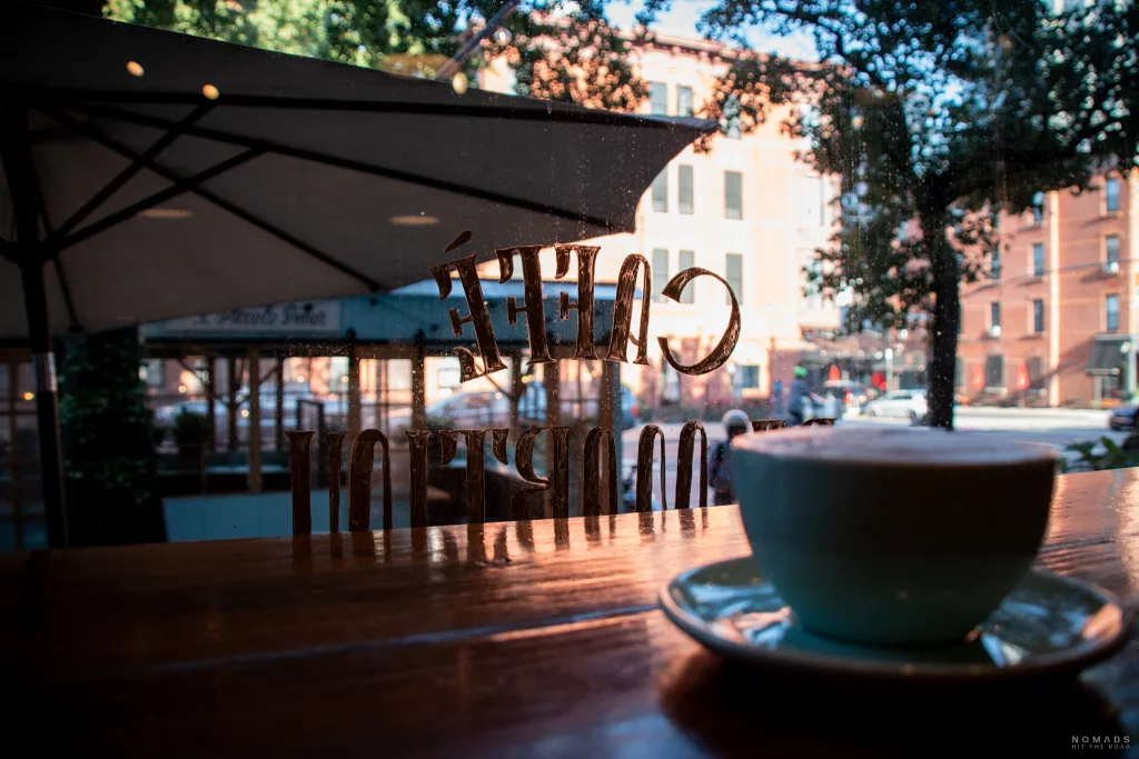 Ausblick auf Scheibe mit Schriftzug Caffè de Martini und im Vordergrund auf Tresen Kaffeetasse