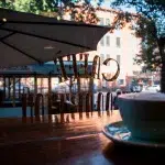 Ausblick auf Scheibe mit Schriftzug Caffè de Martini und im Vordergrund auf Tresen Kaffeetasse