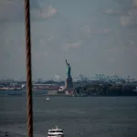 Freiheitsstatue im Hintergrund von Brooklyn Bridge zu sehen sowie ein Boot auf dem Hudson River auf New York City Reise