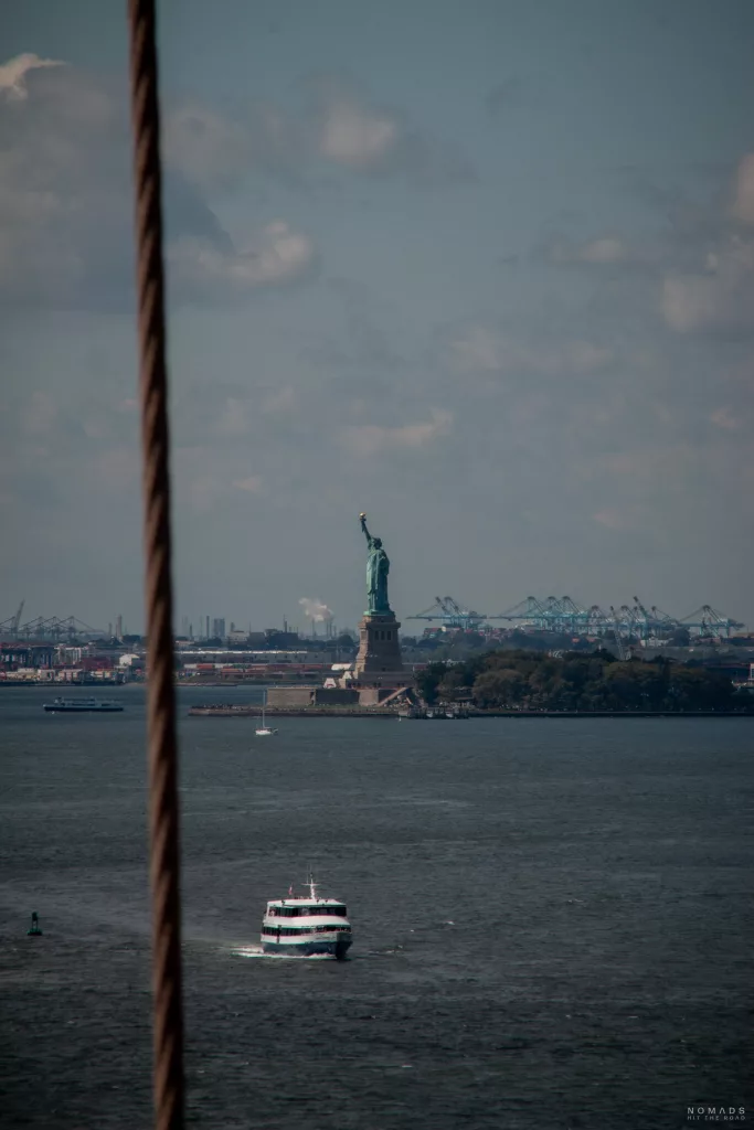 Freiheitsstatue im Hintergrund von Brooklyn Bridge zu sehen sowie ein Boot auf dem Hudson River