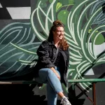 Frau auf Bank sitzend vor einer Graffiti Wand in New York City