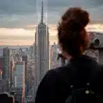 Ausblick vom Rockefeller Center auf das Empire State Building im Hintergrund und Frau im Vordergrund blickt darauf