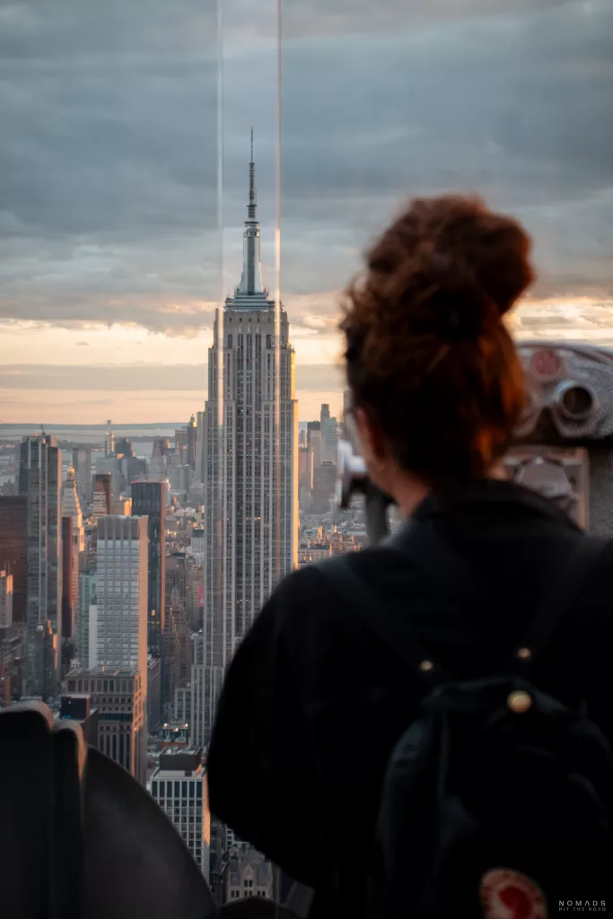 Ausblick vom Rockefeller Center auf das Empire State Building im Hintergrund und Frau im Vordergrund blickt darauf