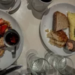 Frühstück mit zwei Tellern, Brot, Ei, Avocado, Pancakes und Getränken