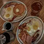 Frühstück iHop mit Eiern, Bacon, Pancakes, Würstchen und Getränken