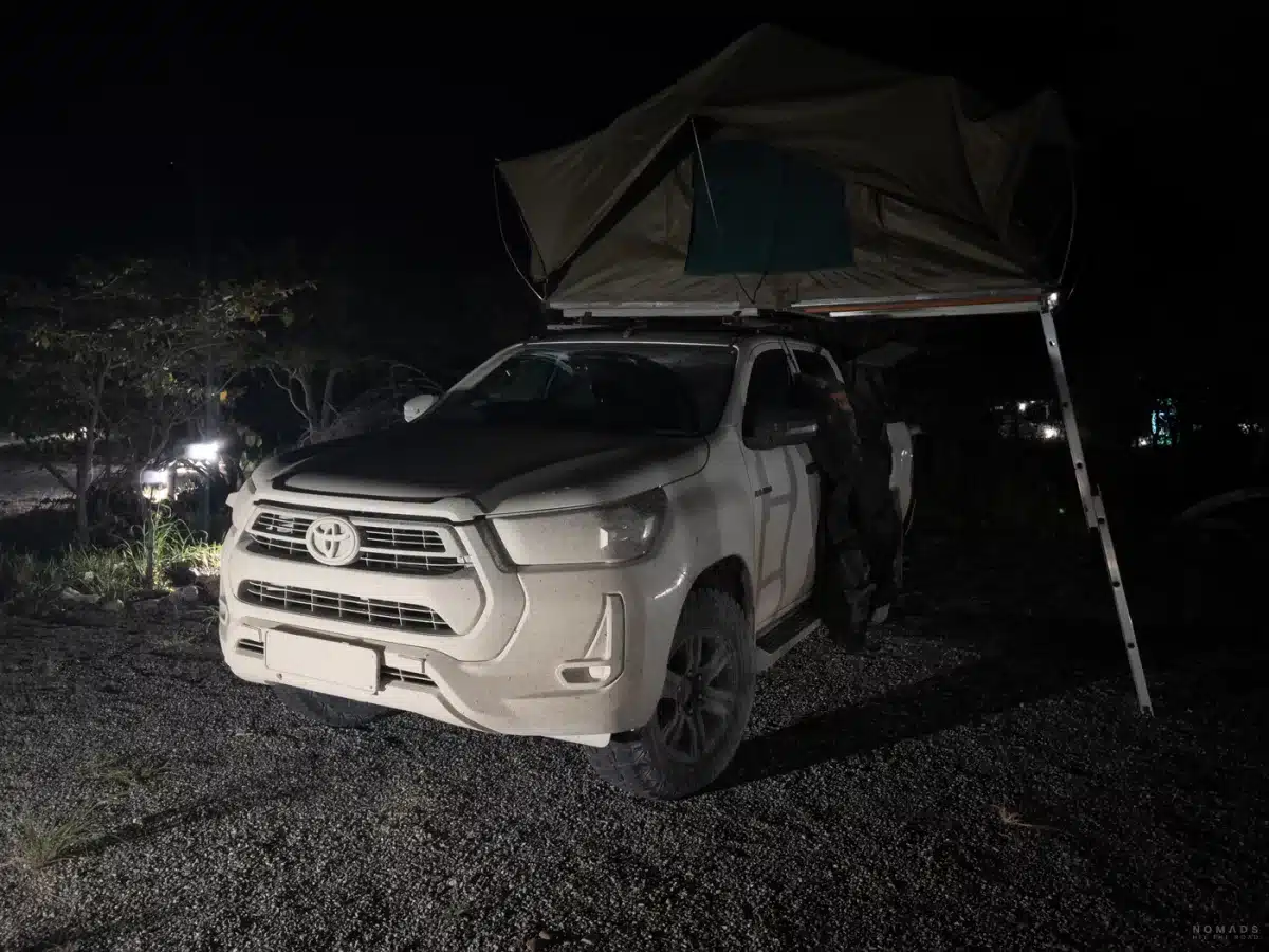 Toyota Hilux mit aufgebautem Dachzelt auf einem Stellplatz der Etosha Village Campsite bei Nacht, beleuchtet von Umgebungslichtern.