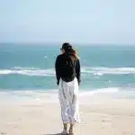 Frau steht am Strand mit Blick auf Meer