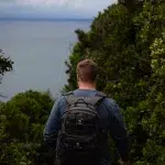 Mann mit Rucksack wandert auf dem Robberg Trail in Plettenberg Bay auf der Garden Route