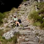 Frau mit Fischerhut sitzt auf Platteklip Gorge Weg