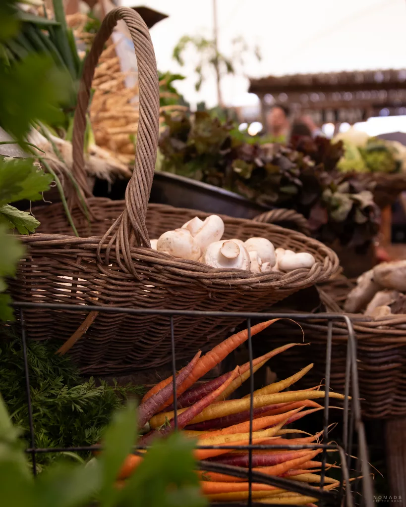 Gemüsestand mit Körben voller Champions und Möhren auf dem Oranjezicht City Farm Market
