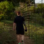 Mann mit Kamera in der Hand läuft an einem Zaum am Kruger National Park entlang