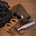 Rucksack, Wanderschuhe, Trekkinghose, Sonnenbrille & Trinkflasche für Packliste Camping oder Safari Reise