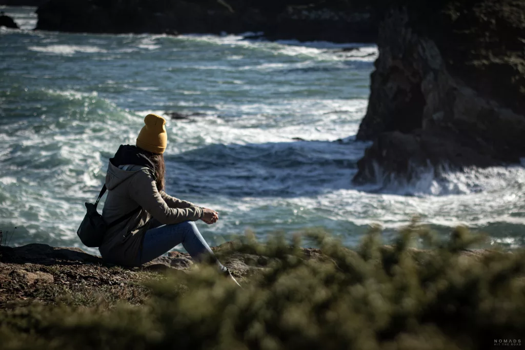 Frau sitzt an den Klippen in Asturien mit dem Meer im Hintergrund