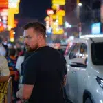 Mann auf der Straße zwischen Fußgängern und Autos in Bangkok Chinatown