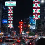 Große Straße im Stadtteil Chinatown in Bangkok bei Nacht mit all seinen Neonlichtern und vielen Autos