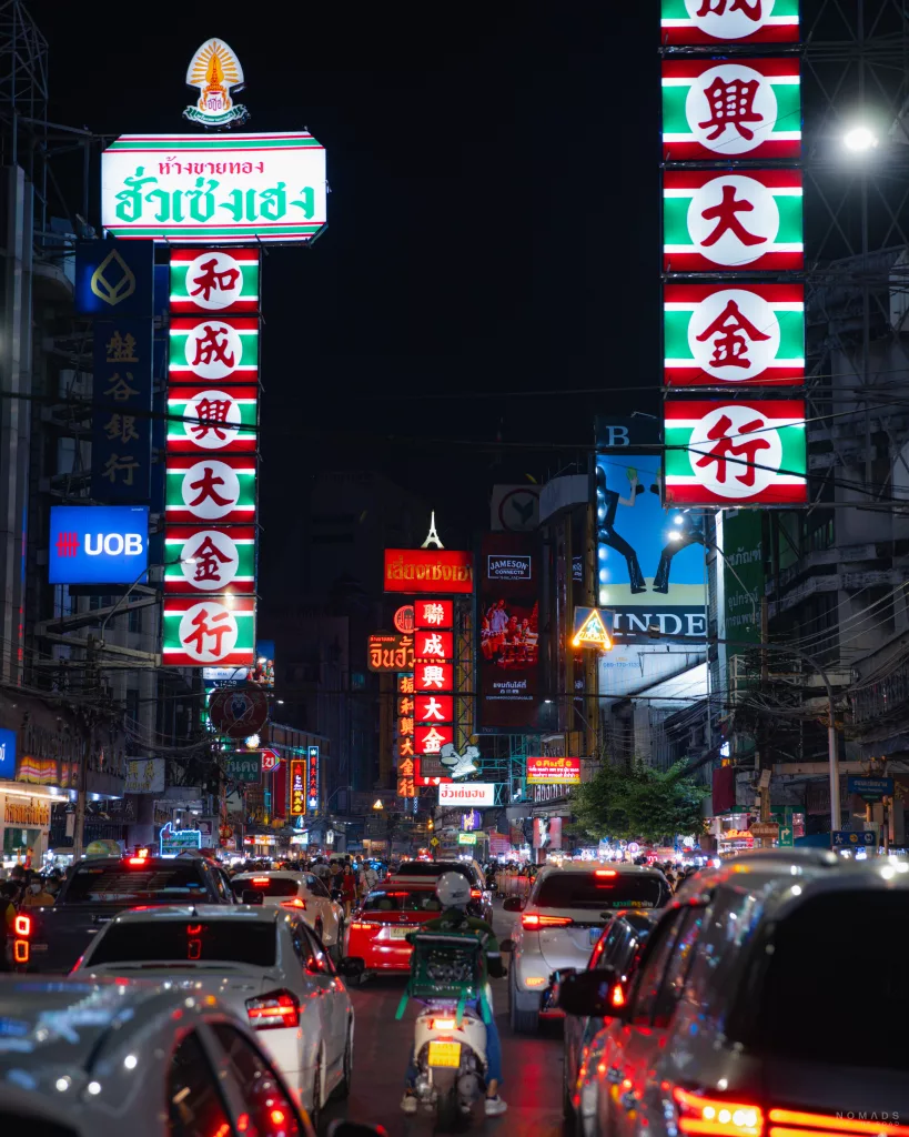 Große Straße im Stadtteil Chinatown in Bangkok bei Nacht mit all seinen Neonlichtern und vielen Autos