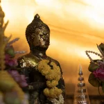 Buddhastatue mit Blumenkranz im Wat Pho