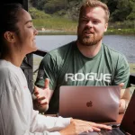 Lachendes Paar am Laptop am See