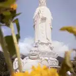 Buddha Statue im Vordergrund während sich im Hintergrund die große Lady Buddha Staue in Da Nang zeigt