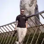 Mann mit Kamera in der Hand steht auf der Golden Hands Bridge in Ba Na Hills in Vietnam