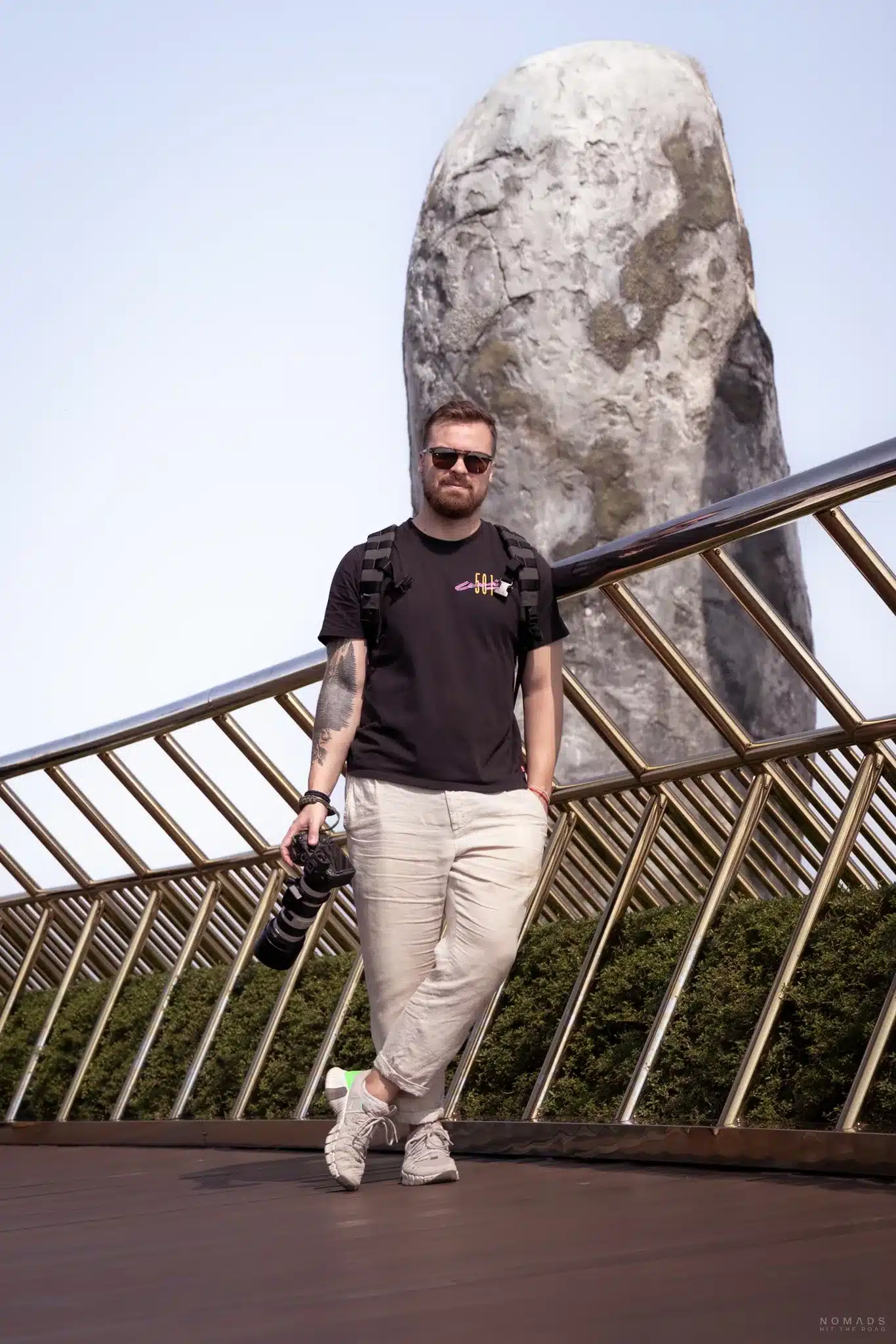 Mann mit Kamera in der Hand steht auf der Golden Hands Bridge in Ba Na Hills in Vietnam