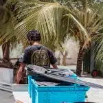 Mitarbeitender der Tauchschule Men of Water mit Tauchequipment auf dem Weg zum Tauchboot