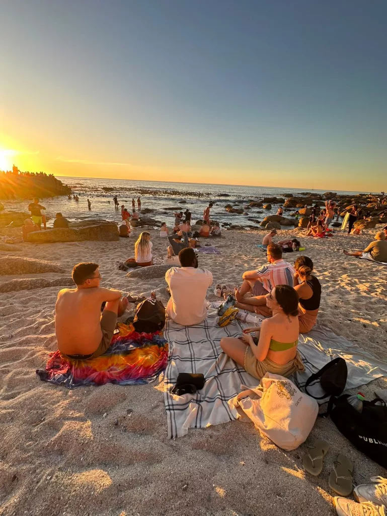 Menschen bei Sonnenuntergang am Strand in Kapstadt