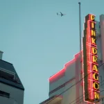 Neonschild mit Flugzeug im Himmel im Hintergrund