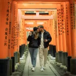 Pärchen läuft durch die orangenen Tore des Fushimi-Inari-Taisha Schreins in Kyoto