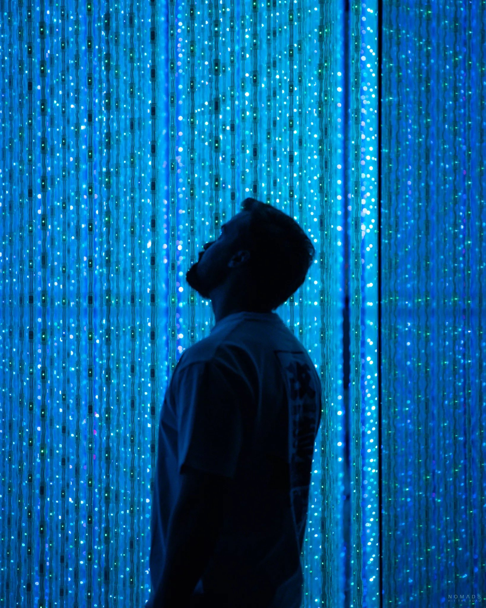 Mann vor einer blauen Lichterkettenwand