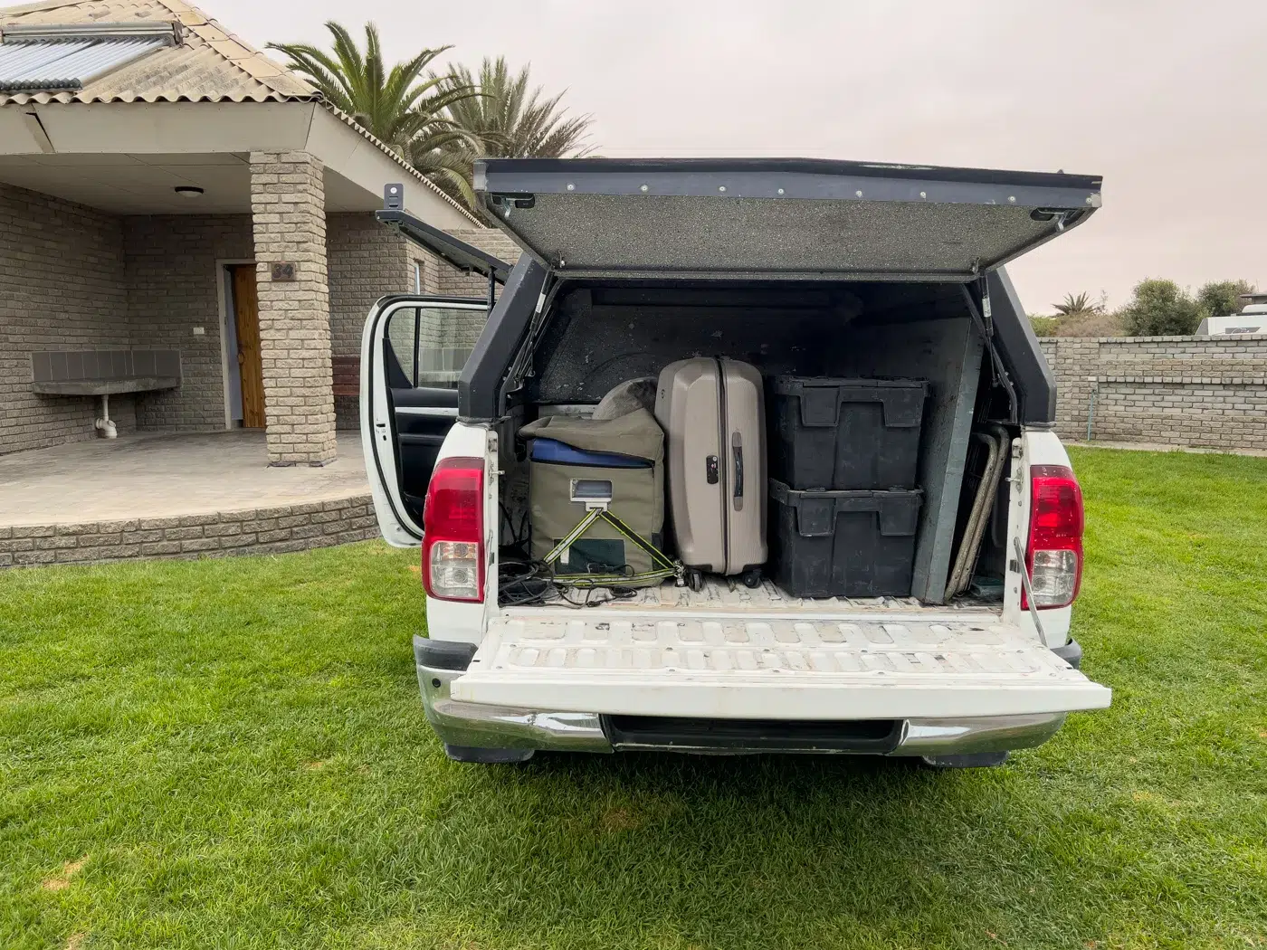 Rückansicht des Pick-ups mit geöffnetem Heckdeckel, gut sichtbar: beladene Ladefläche mit Campingausrüstung, Koffer und Boxen.