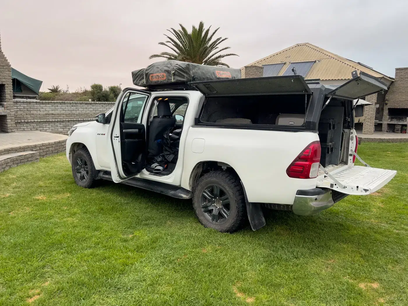 Pick-up Mietwagen mit geöffnetem Heckdeckel, zeigt die beladene Ladefläche mit Koffern, Campingausrüstung und Stauboxen.