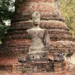 Zerbrochene Buddha Statue vor einem rot geziegelten Chedi