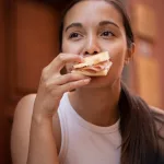 Frau isst ein Mortadella Sandwich