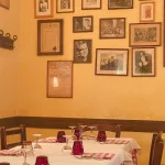 Gedeckter Tisch mit Gläsern und Tischdecke und Bildern an der Wand in einem Restaurant
