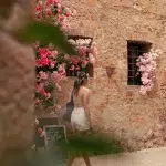 Frau läuft durch Gasse mit rosa und pinken Blumen