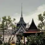 Traditioneller thailändischer Tempel in Ancient City, Thailand, umgeben von grünen Bäumen und kunstvollen Dächern.