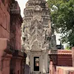 Ein detaillierter Eingang zu einer Grabstätte mit aufwendigen Schnitzereien in der Ancient City, der die traditionelle thailändische Architektur zeigt.