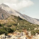 Berglandschaft im Pirin Gebirge mit schroffen Gipfeln und bewachsenen Hängen im Vordergrund