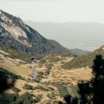 Blick auf das Tal im Pirin Gebirge mit Bergen links und rechts und einem schlängelnden Fluss.