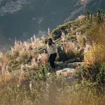 Wanderin inmitten einer alpinen Landschaft, umgeben von blühenden Pflanzen und Bergvegetation im Pirin-Gebirge.