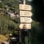 Wegweiser mit verschiedenen Wanderzielen im Pirin-Gebirge, darunter Vihren-Hütte und Muratovo-See, mit umliegenden Berglandschaften.
